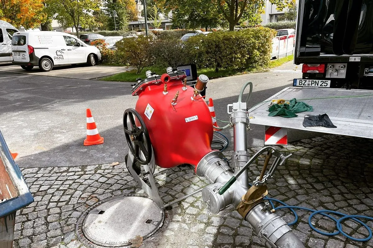 Liner-Technik an einem geöffneten Schacht in einer gepflasterten Straße
